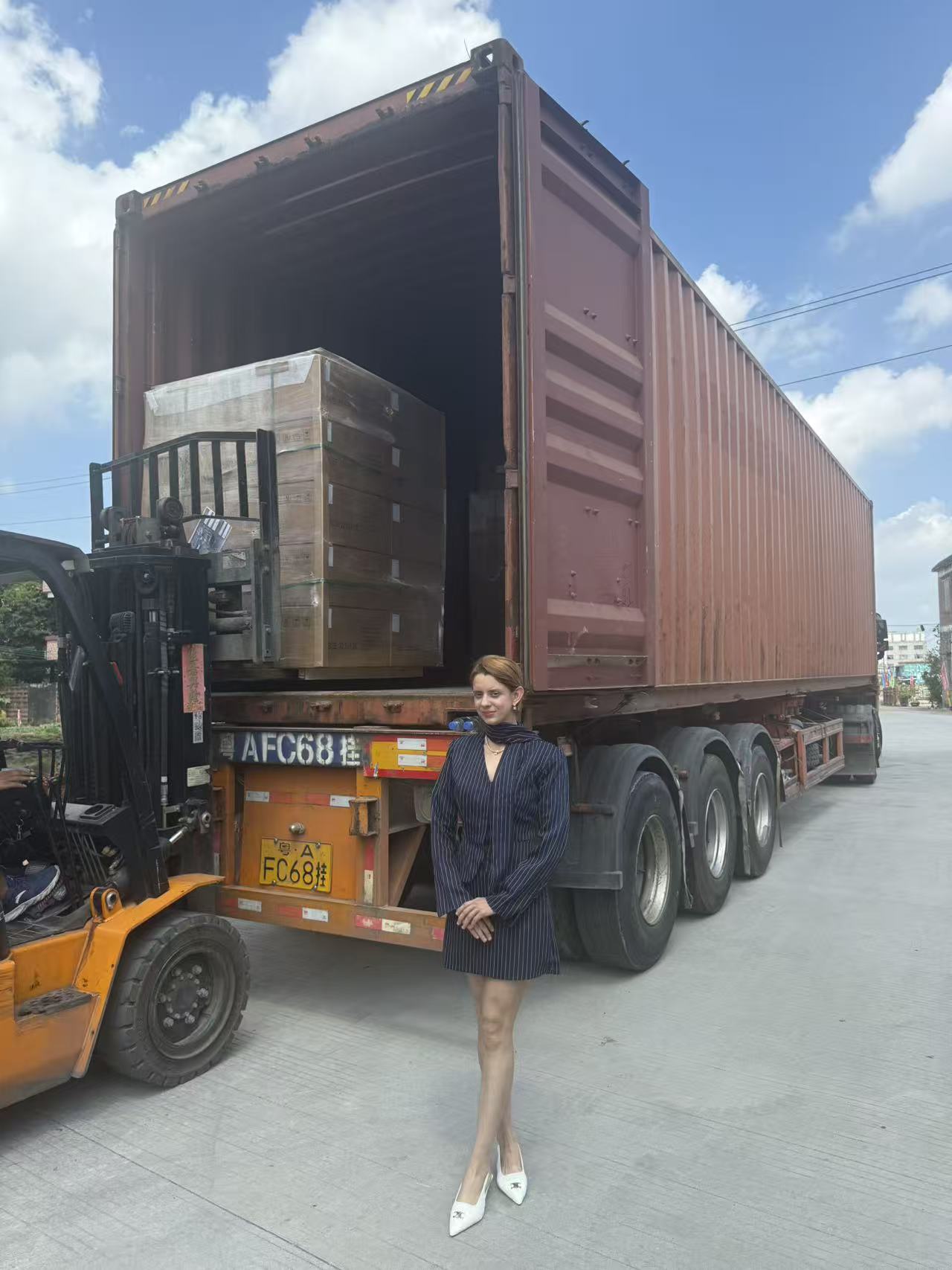 叉车向集装箱装货，物流人员在旁协助 / Montacargas cargando mercancía en un contenedor con personal logístico